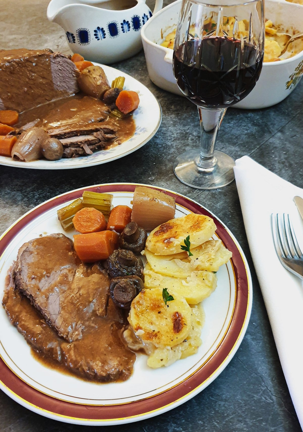 Slices of boeuf bourguignon on a plate with vegetables, covered in gravy.