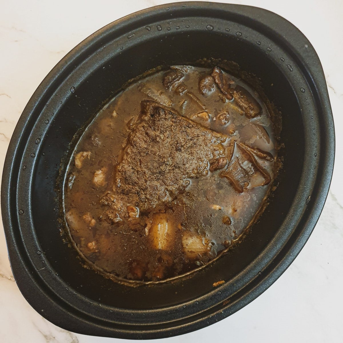 A slow-cooker containing a cooked dish of boeuf bourguignon.