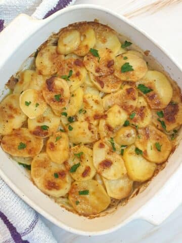 A dish of boulangere potatoes with a crispy cheese topping.