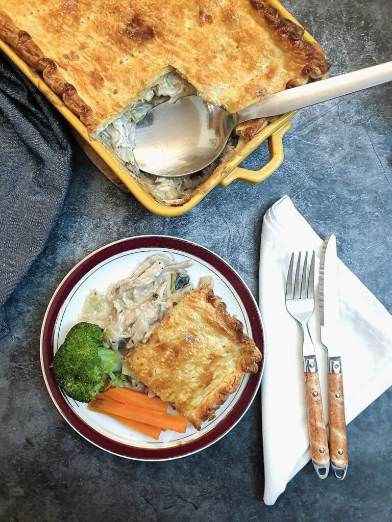 A slice of chicken leek and mushroom pie being lifted from a dish.