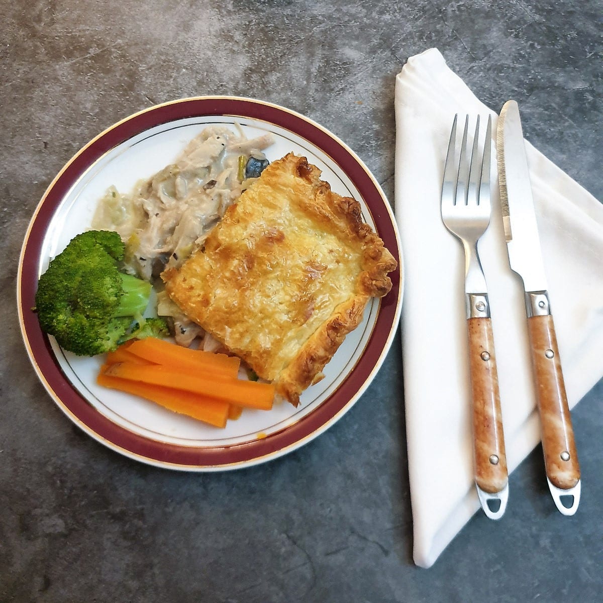 A plate of chicken, leek and mushroom pie with vegetables.