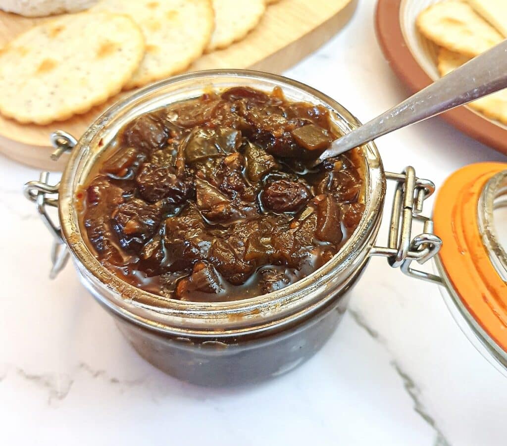 An open jar of green tomato chutney.