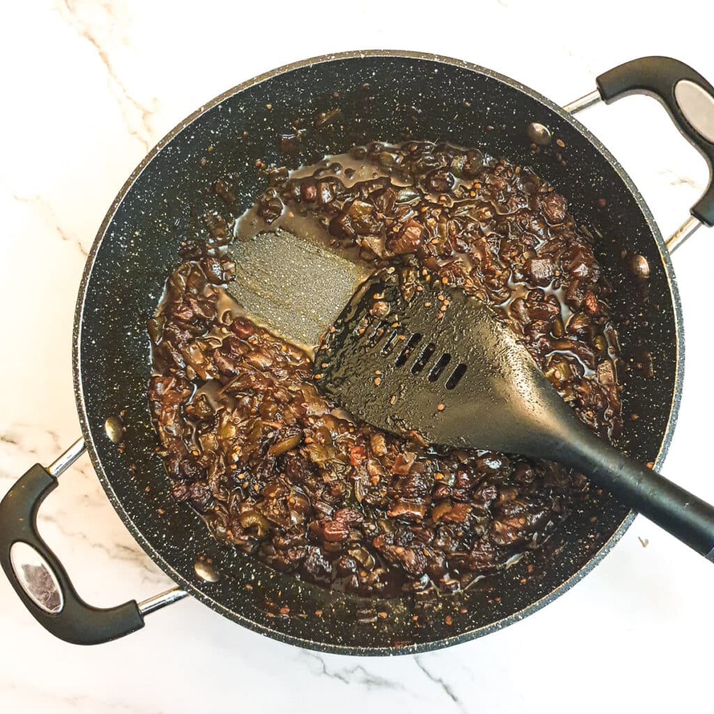 Green tomato chutney in a pan, showing how the chutney leaves a trail in the pan.