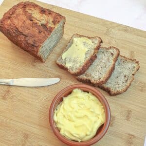 Three slices of per and banana load next to a dish of butter.