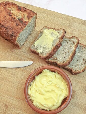 Three slices of per and banana load next to a dish of butter.