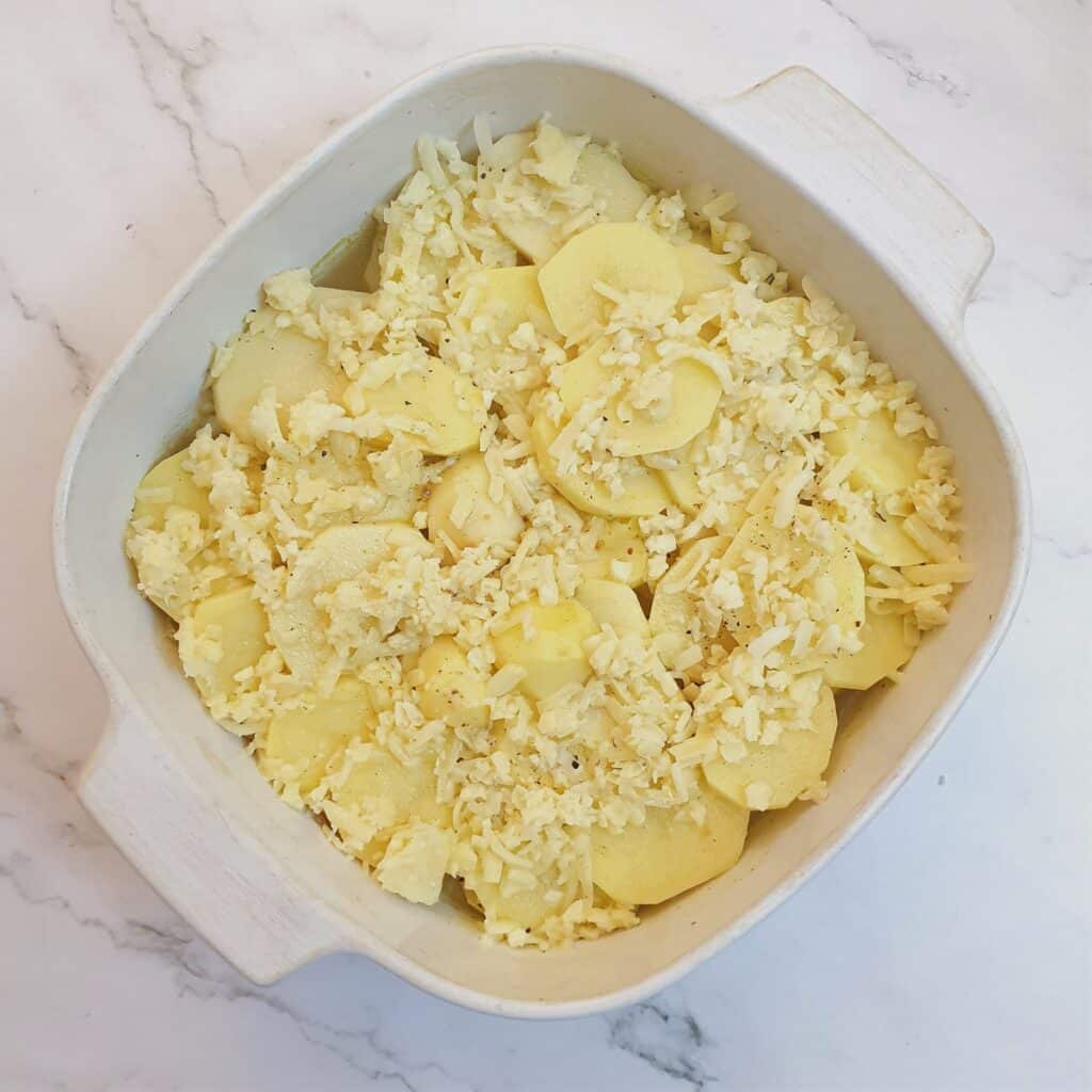 Boulangere potatoes in a baking dish ready for the oven.