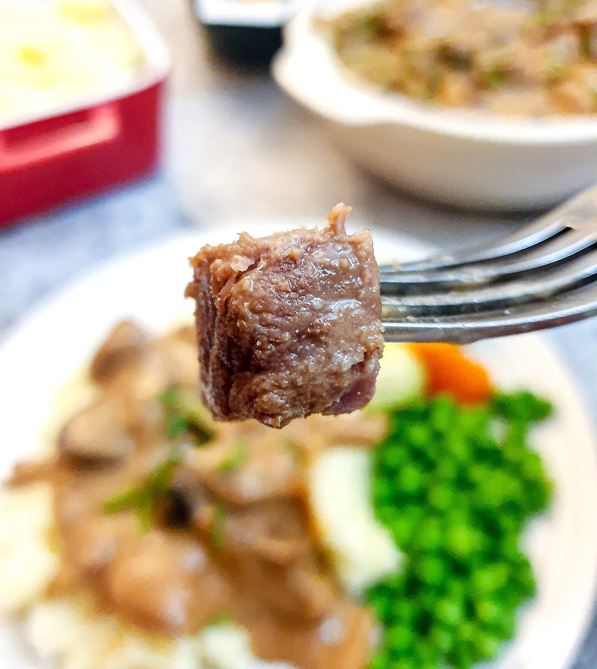 Close up of a piece of cooked beef stroganoff steak on a fork.