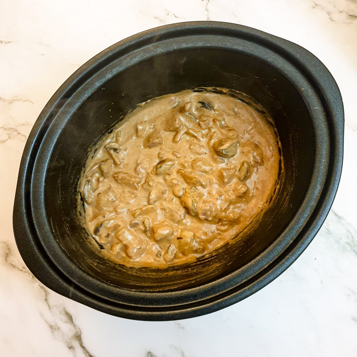 Beef stroganoff mixed with sour cream in a slow-cooker.