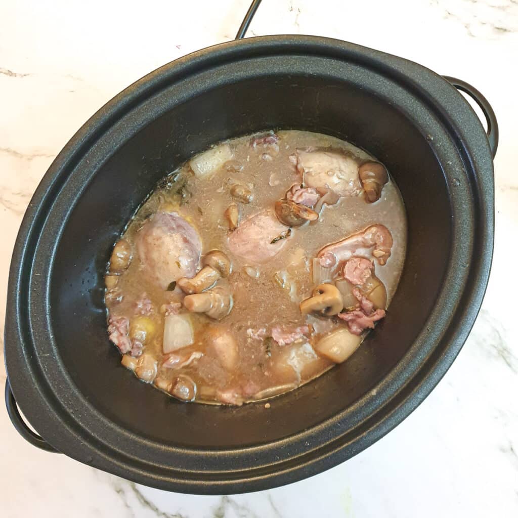 Fully cooked coq au vin in a slow-cooker.