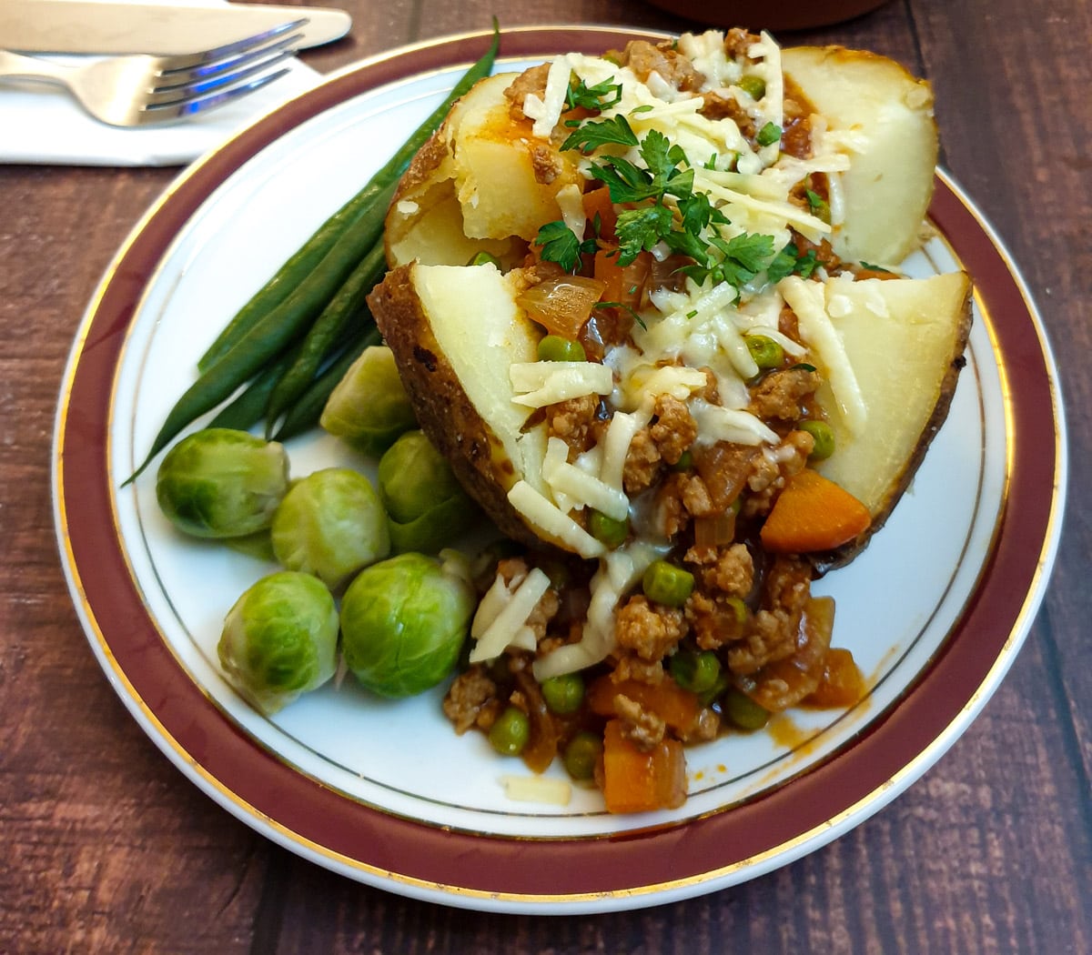 Close up of a baked potato covered with mince and cheese.