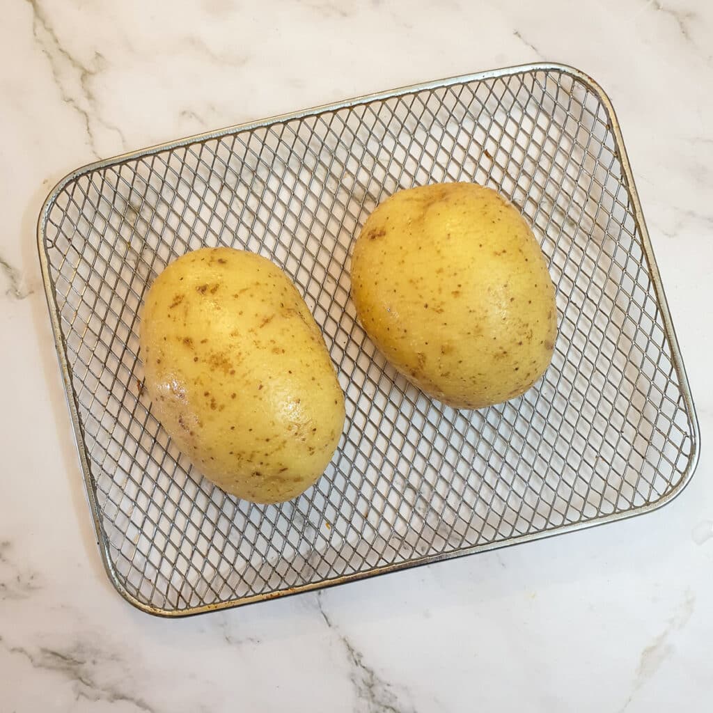 Two potatoes on an air-fryer rack.