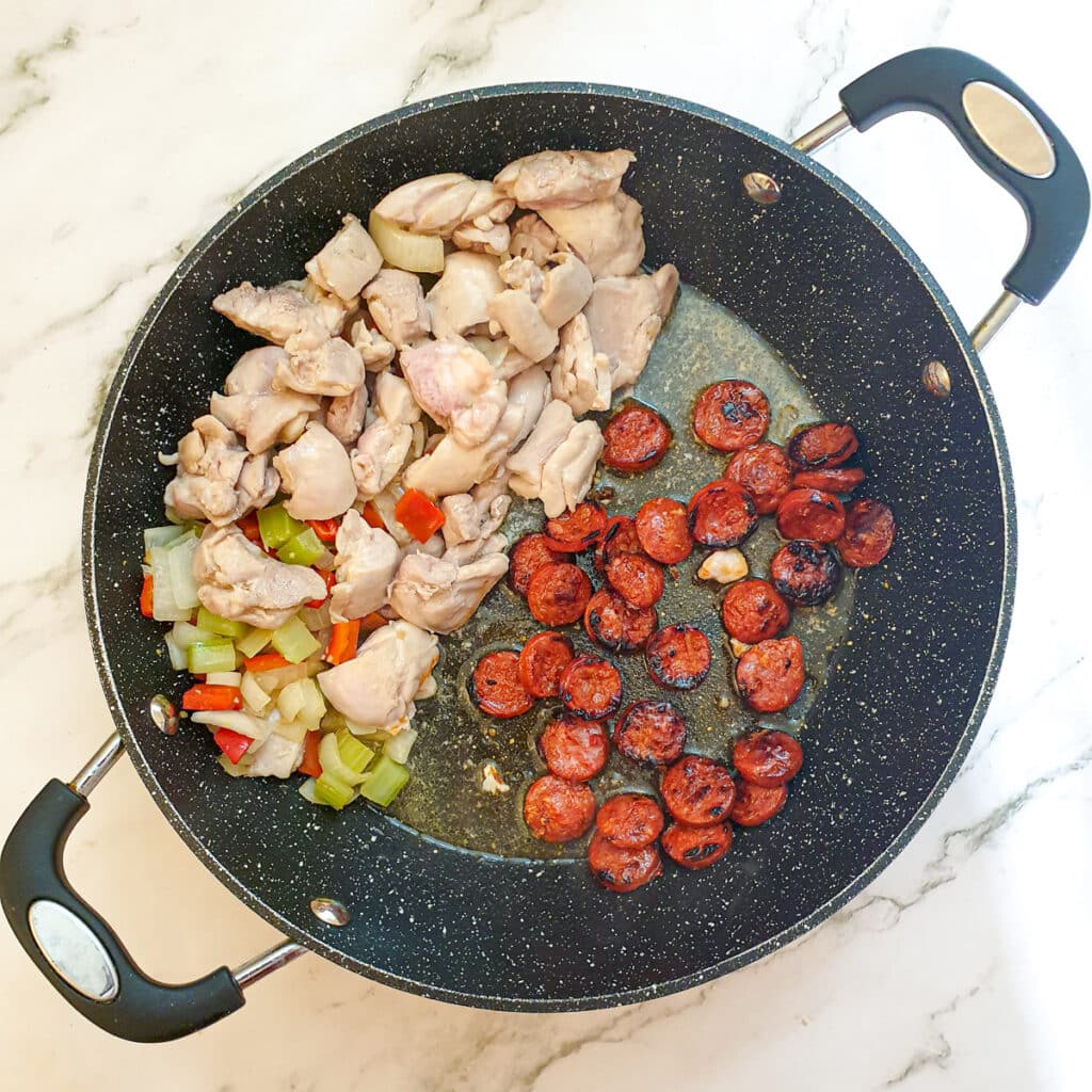 Chorizo sausage being browned in a pan.