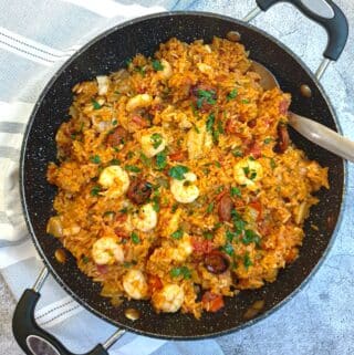 Creole jambalaya in a large pan with a serving spoon.