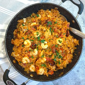 Creole jambalaya in a large pan with a serving spoon.