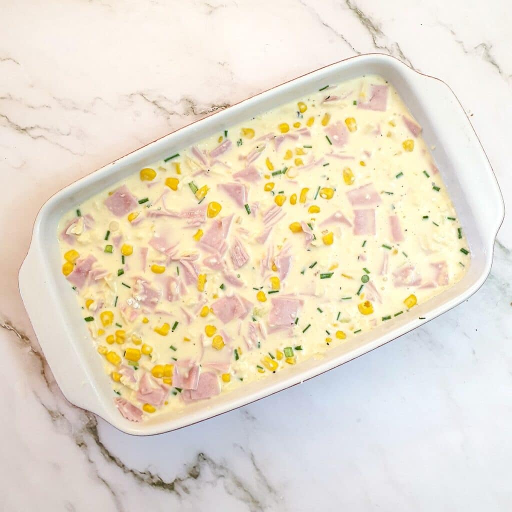 Ham, cheese and sweetcorn in a baking dish covered with a mixture of milk and cream.