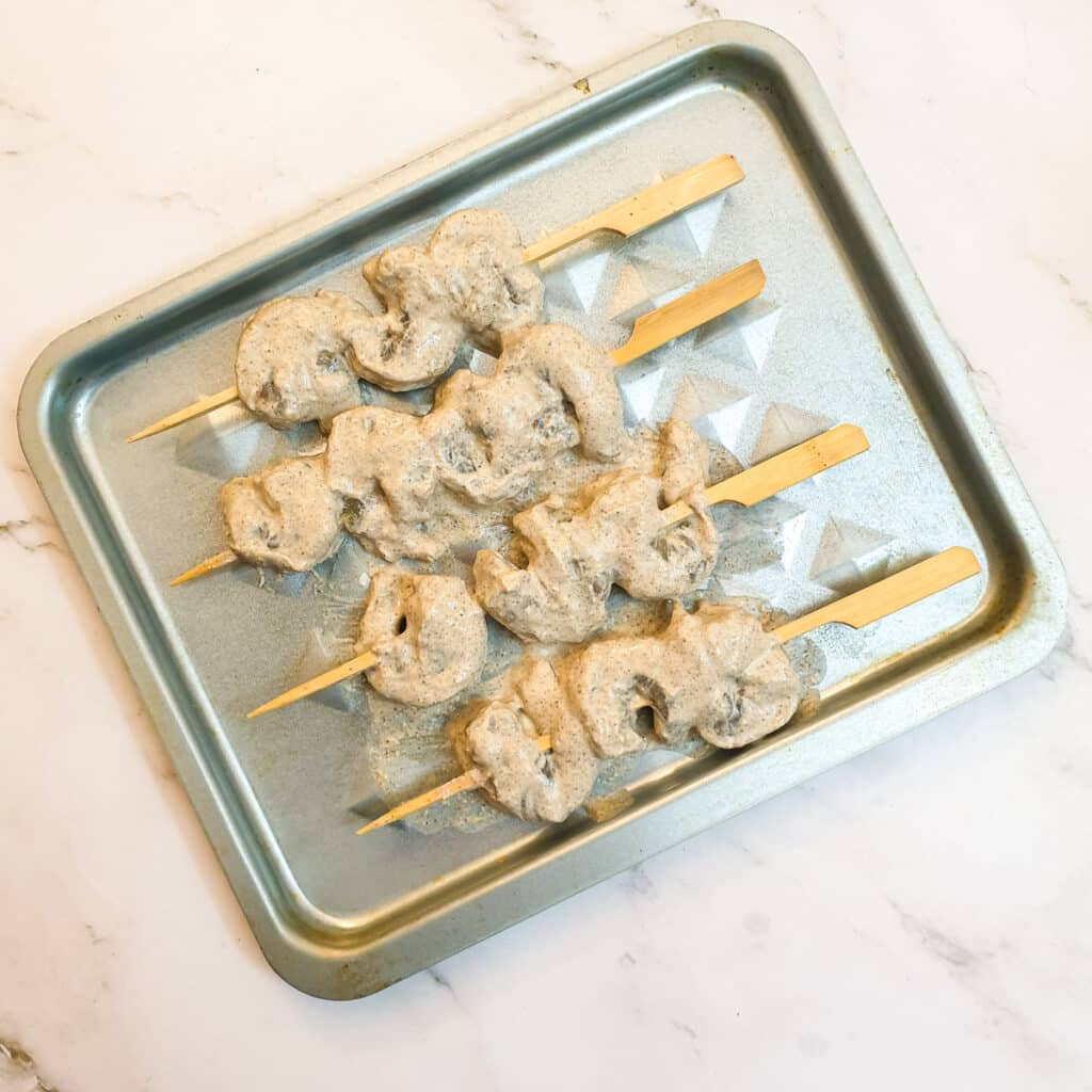 Raw prawn skewers on an air fryer tray.