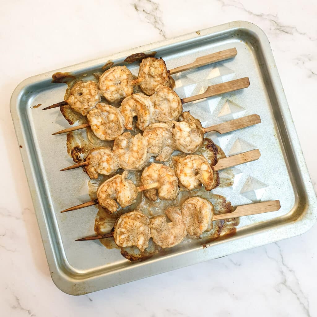 Cooked prawn skewers on an air fryer tray.