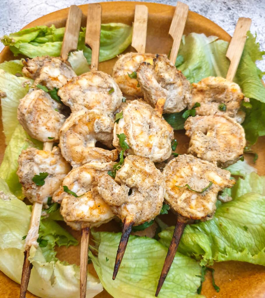 Close up of curried prawn skewers on a bed of lettuce.