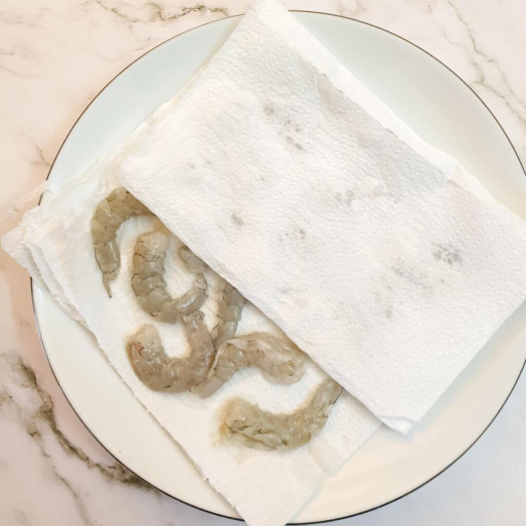 Peeled prawns on a plate with paper towel.