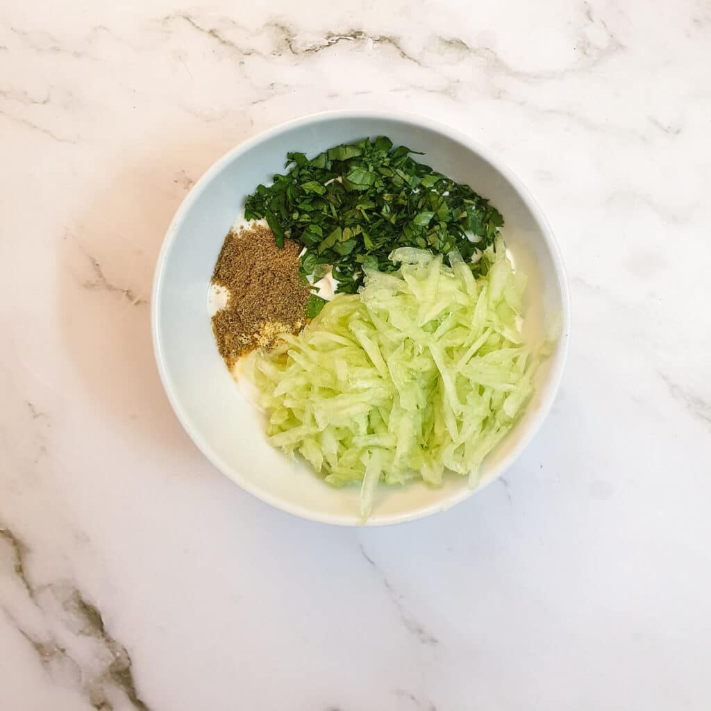 Ingredients for cucumber raita in a mixing bowl.