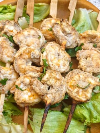 Close up of curried prawn skewers on a bed of lettuce.