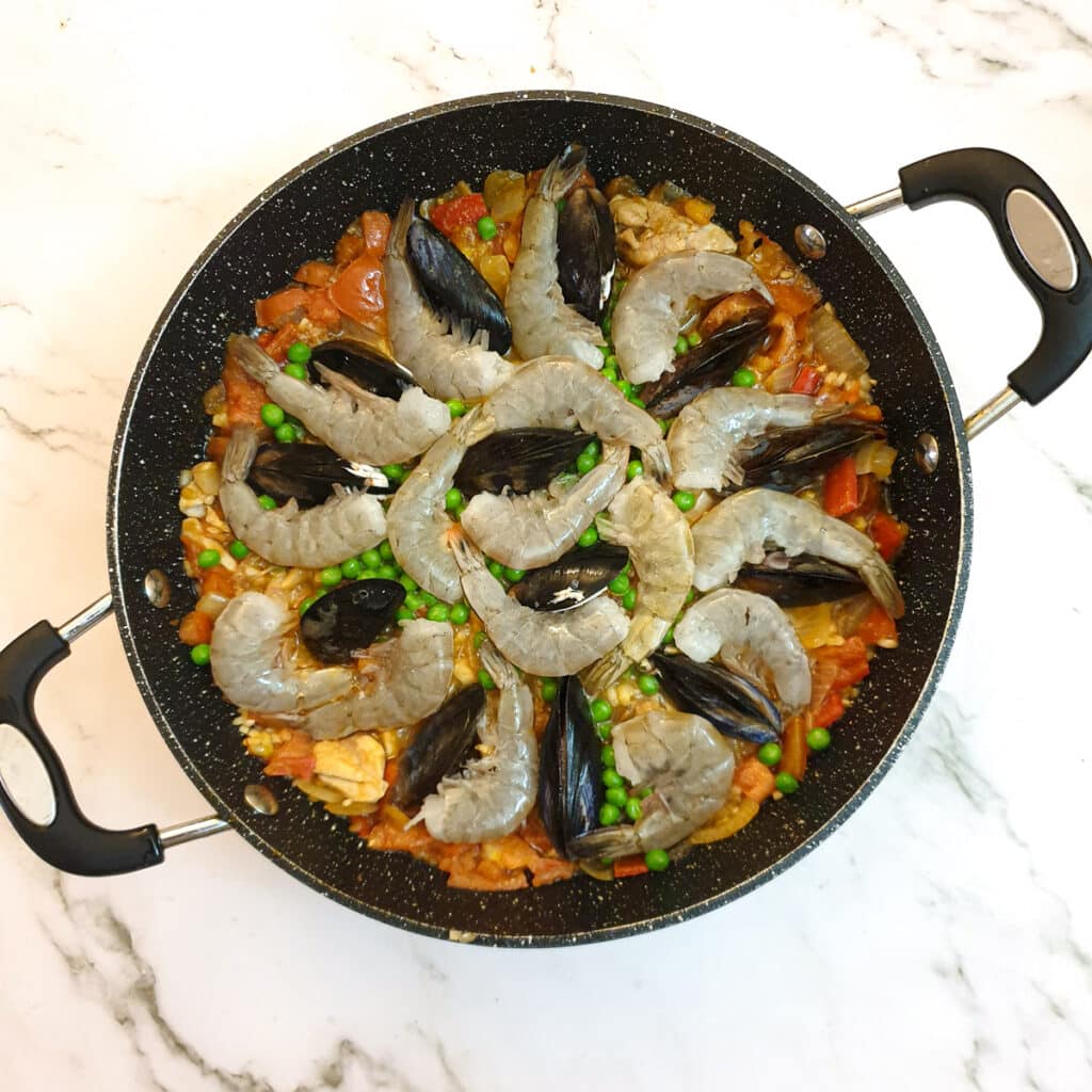 A pan of paella after the prawns and mussels have been added.