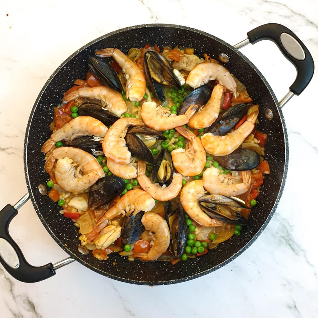 A pan of paella after the prawns have turned pink and the mussels have opened.
