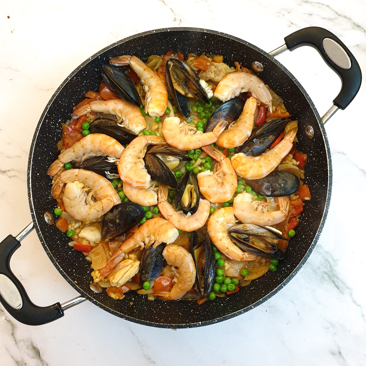 A pan of paella after the prawns have turned pink and the mussels have opened.