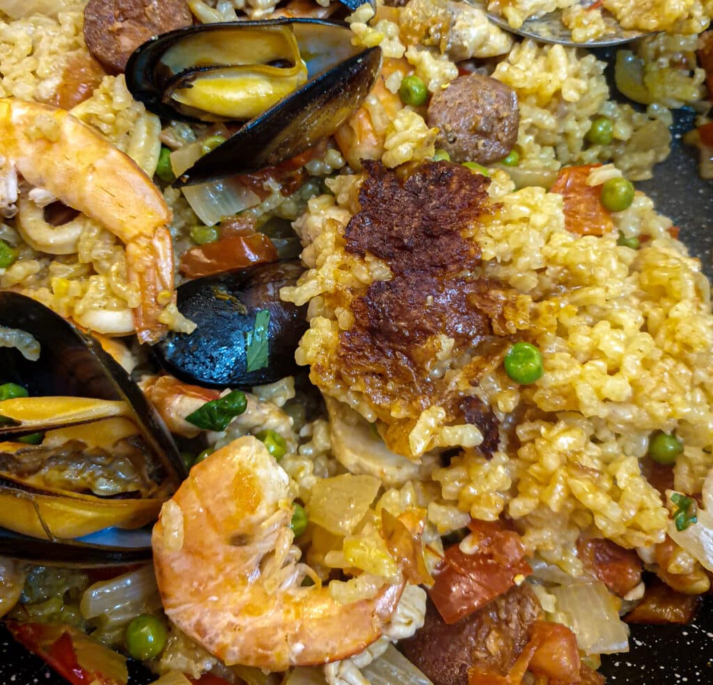 Rice turned over in the paella to show the socarrat on the base.