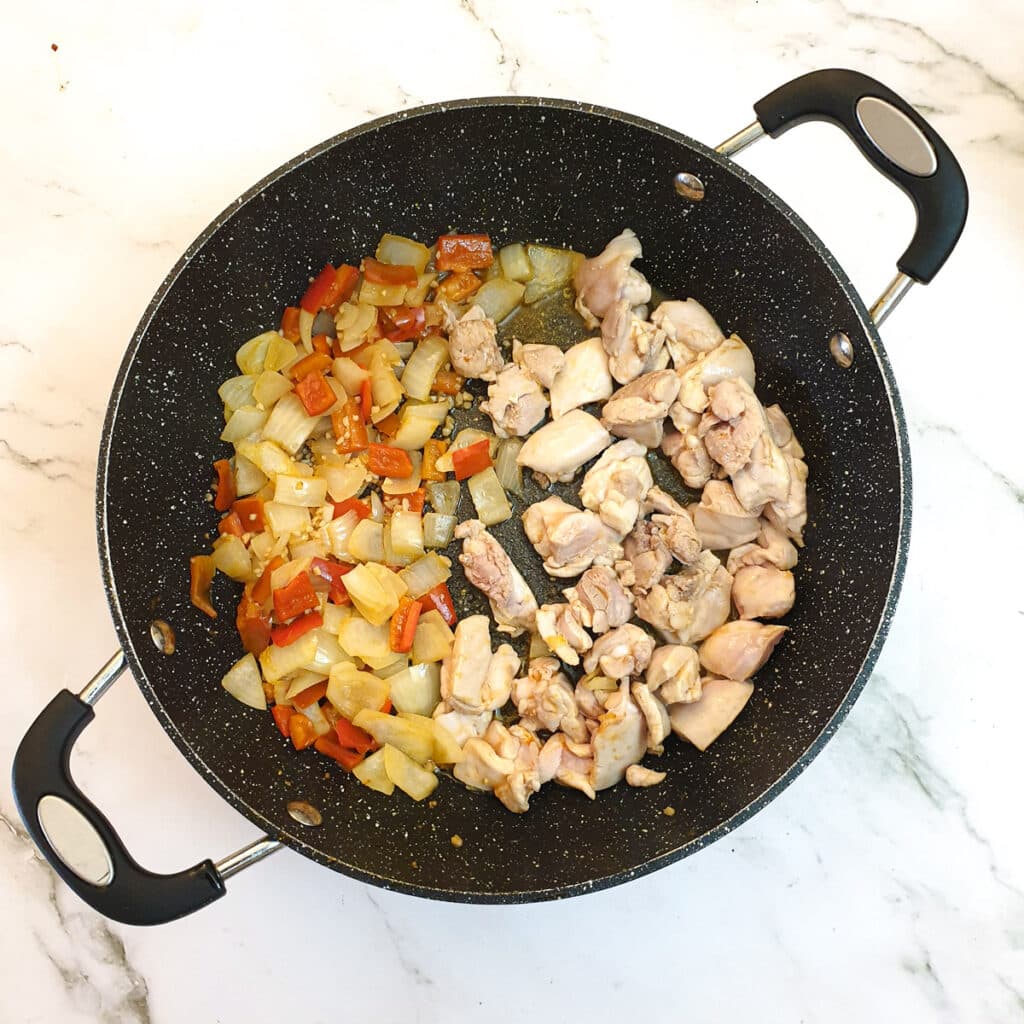 Pieces of chicken being lightly fried in a pan.