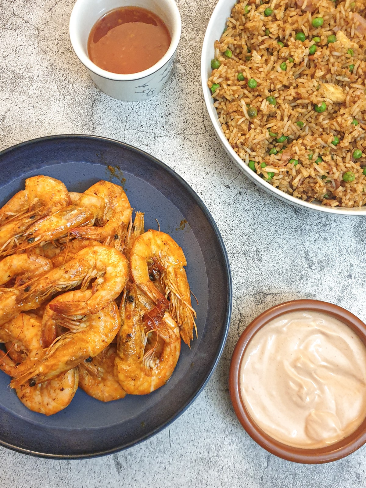 Garlic butter prawns with a dish of rice and a dipping sauce.