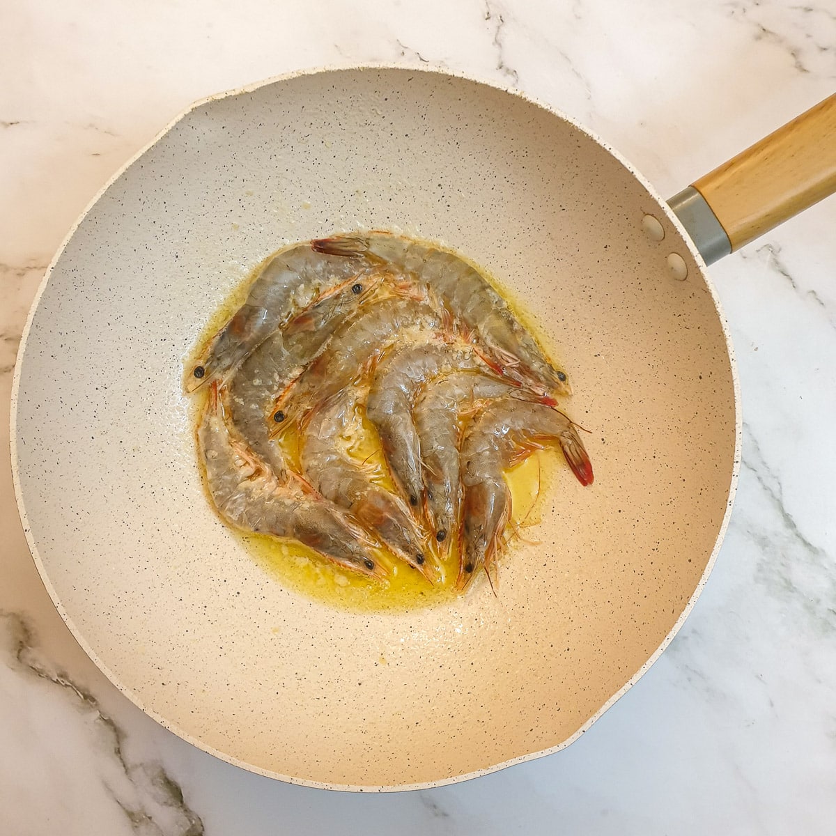 Garlic butter prawns being cooked on one side.