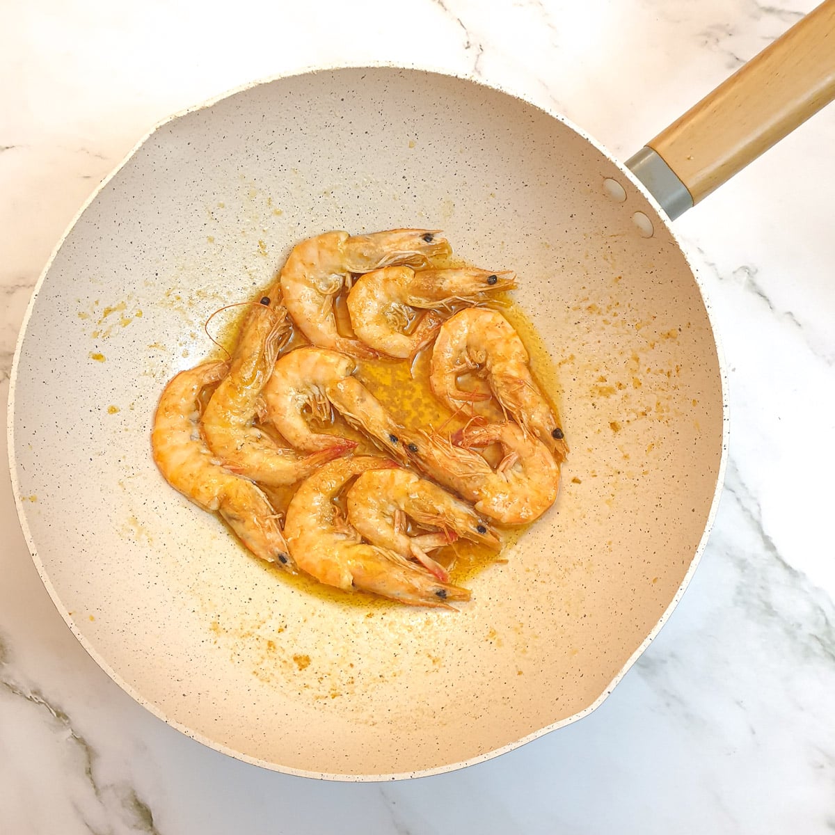 Garlic butter prawns that have been cooked until pink, in a wok.