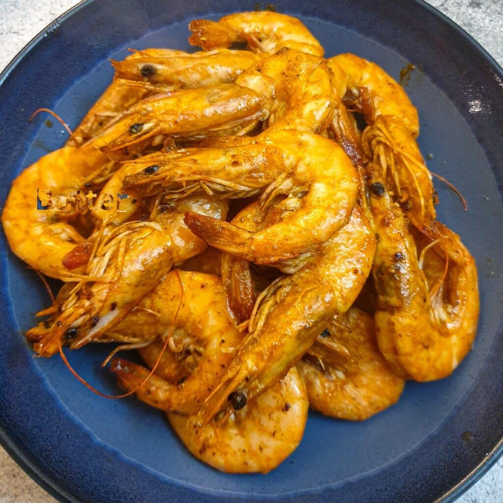 A pile of garlic butter prawns on a serving dish.