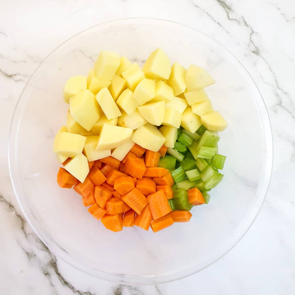 Chopped celery, potatoes and carrots in a bowl.