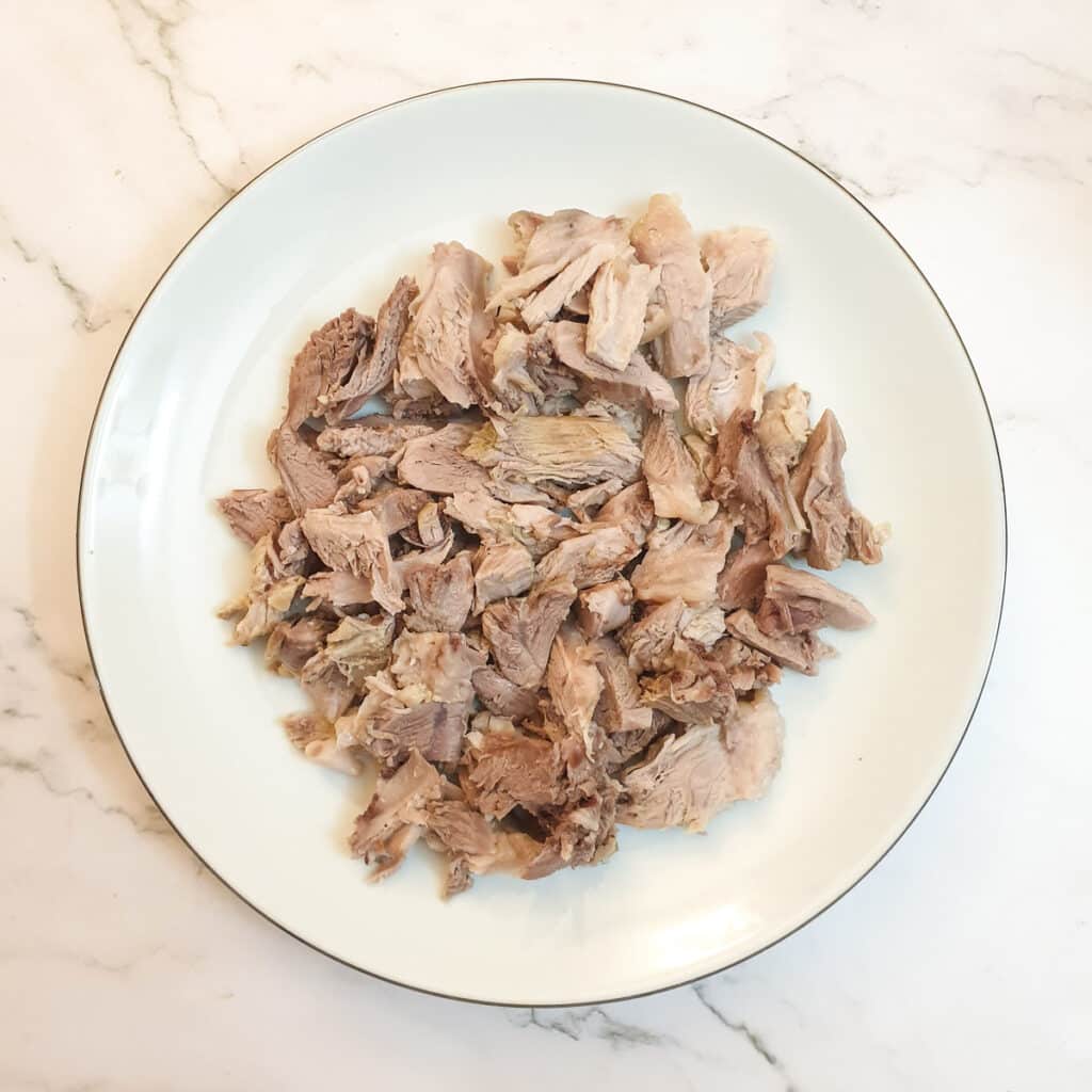 Shredded ham hock on a white plate.