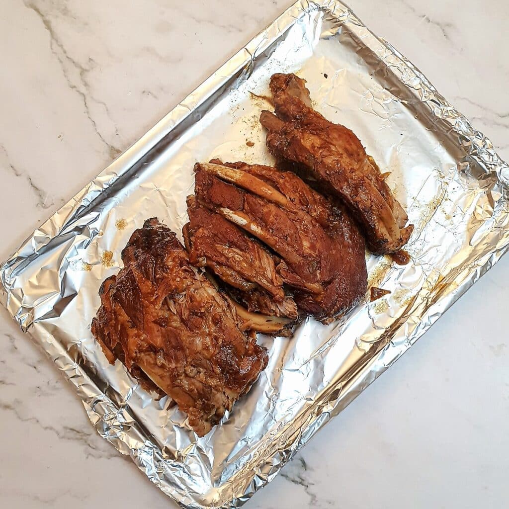 Cooked pork spare ribs on a baking sheet.