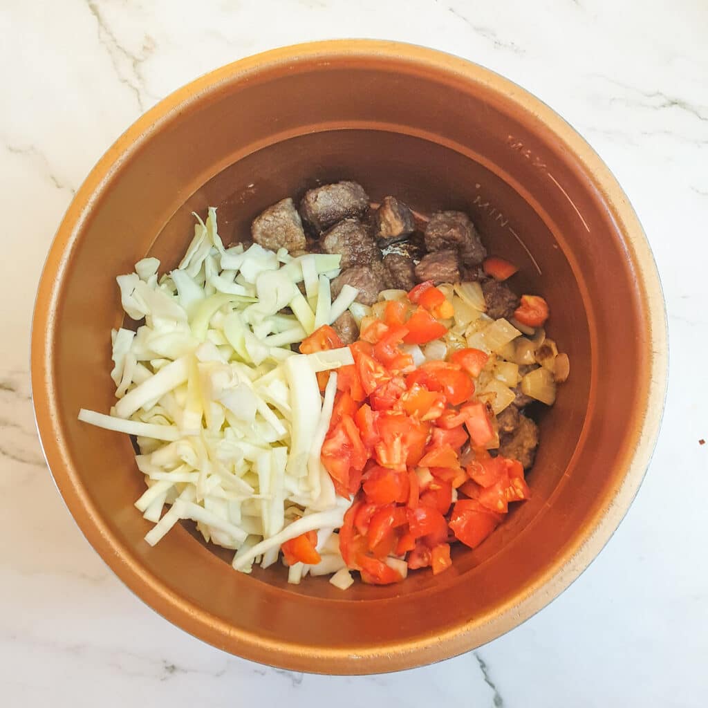 Steak, kidney, tomatoes, onions and shredded cabbage in a pressure cooker.