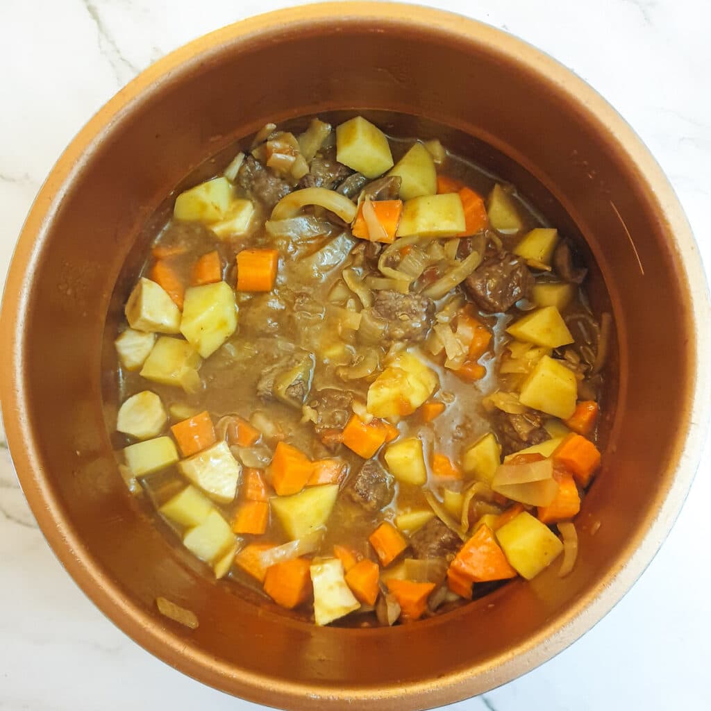 Potatoes and carrots being added to the pressure cooker.