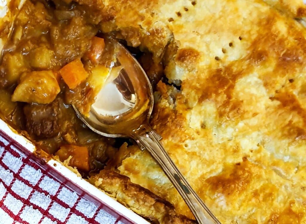 Steak and kidney pie with a corner removed to show the filling.