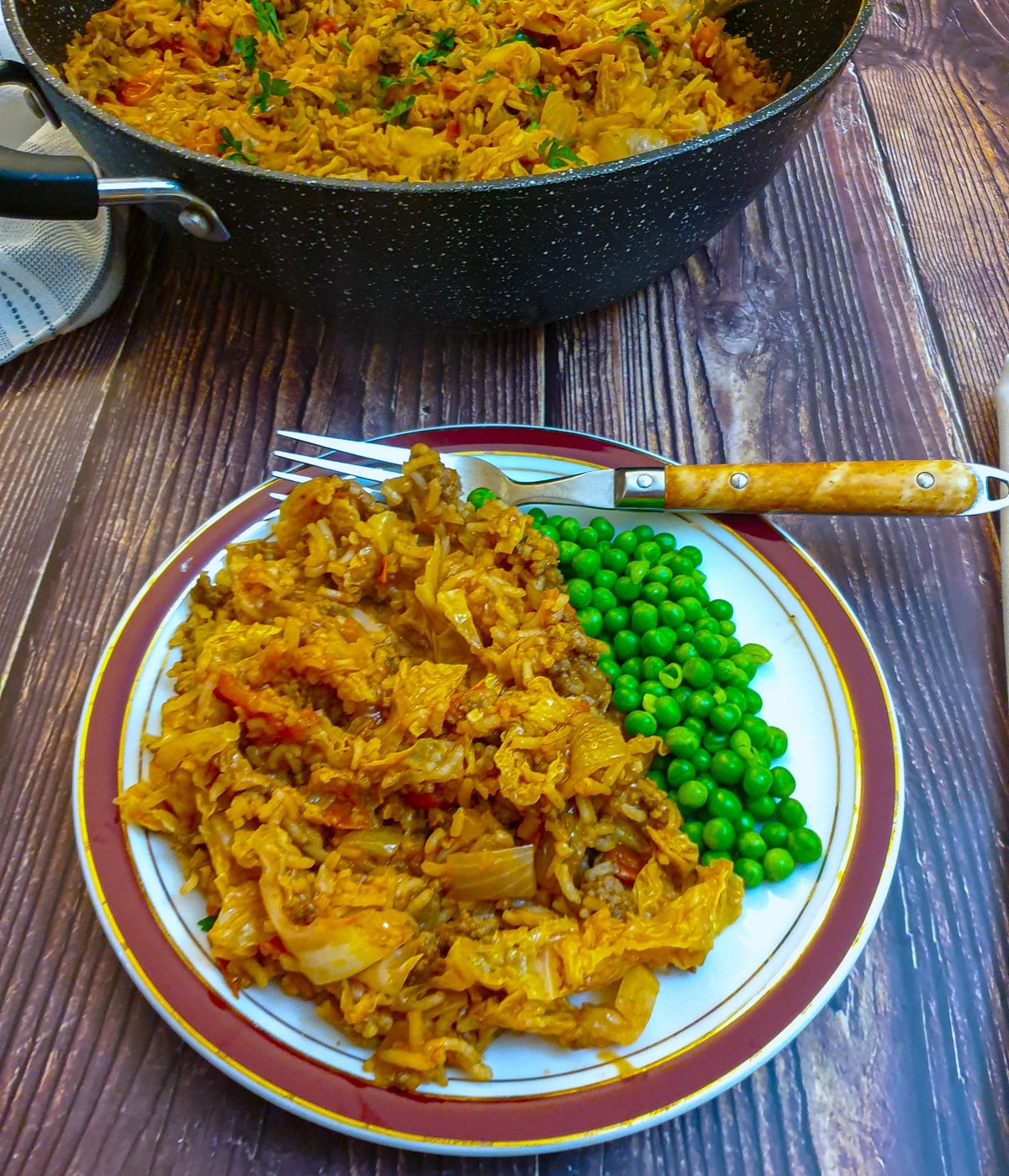 A plate of unstuffed cabbage rolls with a helping of garden peas.