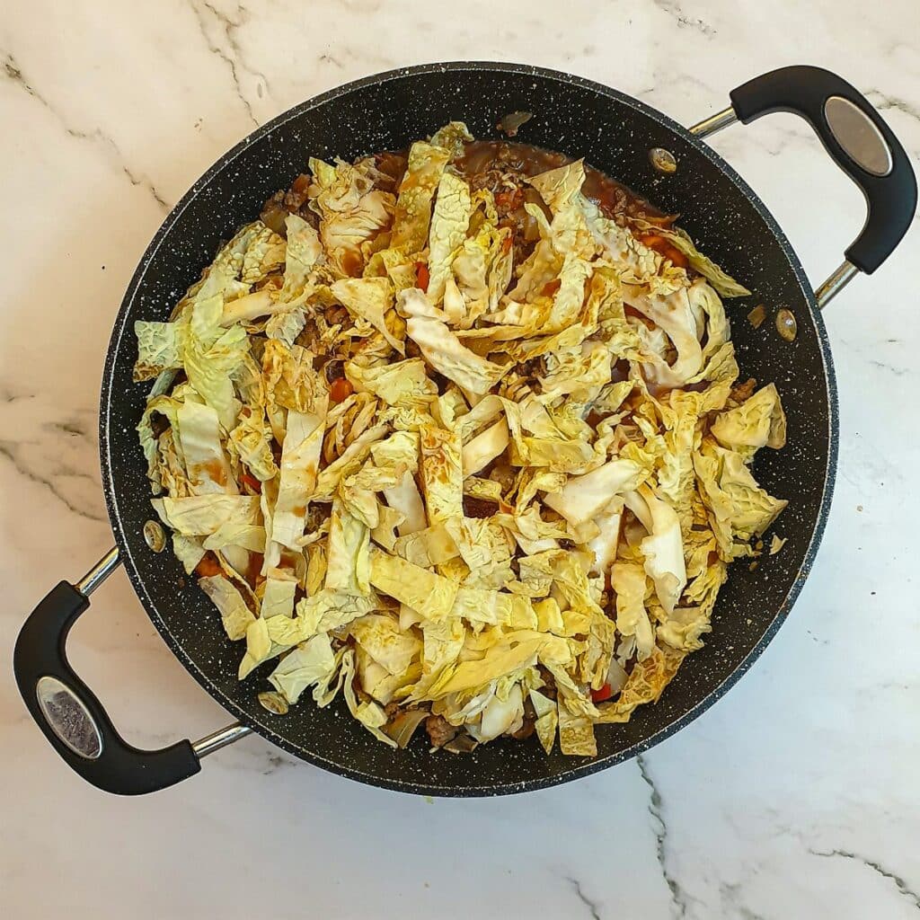 Shredded cabbage being added to the pan.