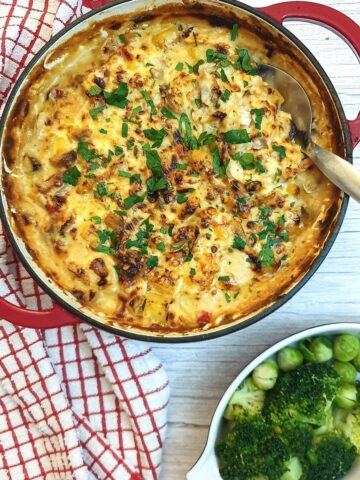 Overhead shot of a cheesy potato and chicken bake in a red casserole dish.