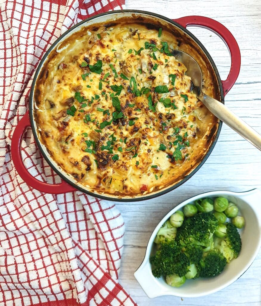 Overhead shot of a cheesy potato and chicken bake in a red casserole dish.