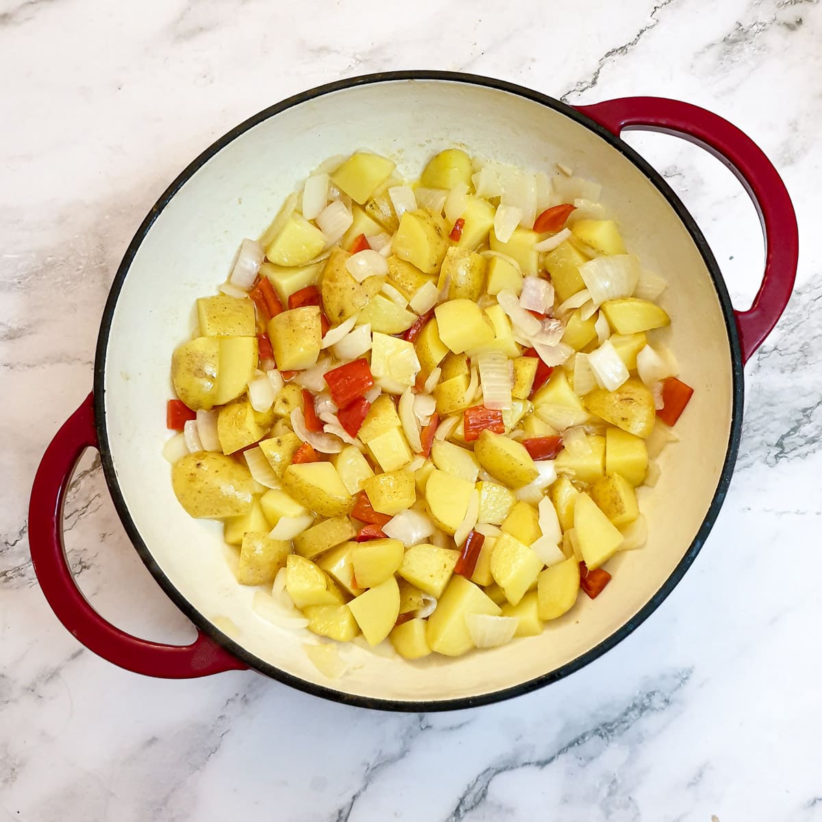 Potatoes, onions and peppers in a frying pan.