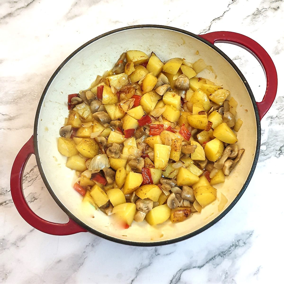 Potatoes, onions, red peppers and mushrooms after having been cooked.