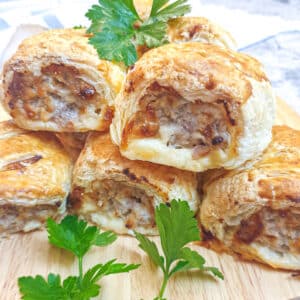 A pile of cheese and onion pork sausage rolls on a plate.