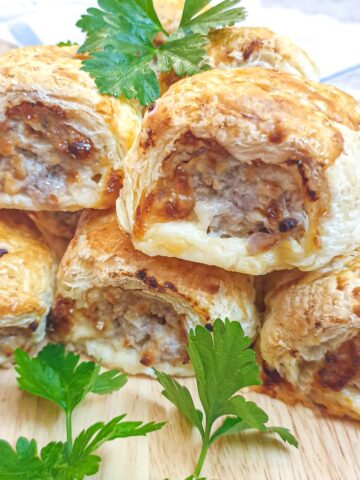 A pile of cheese and onion pork sausage rolls on a plate.