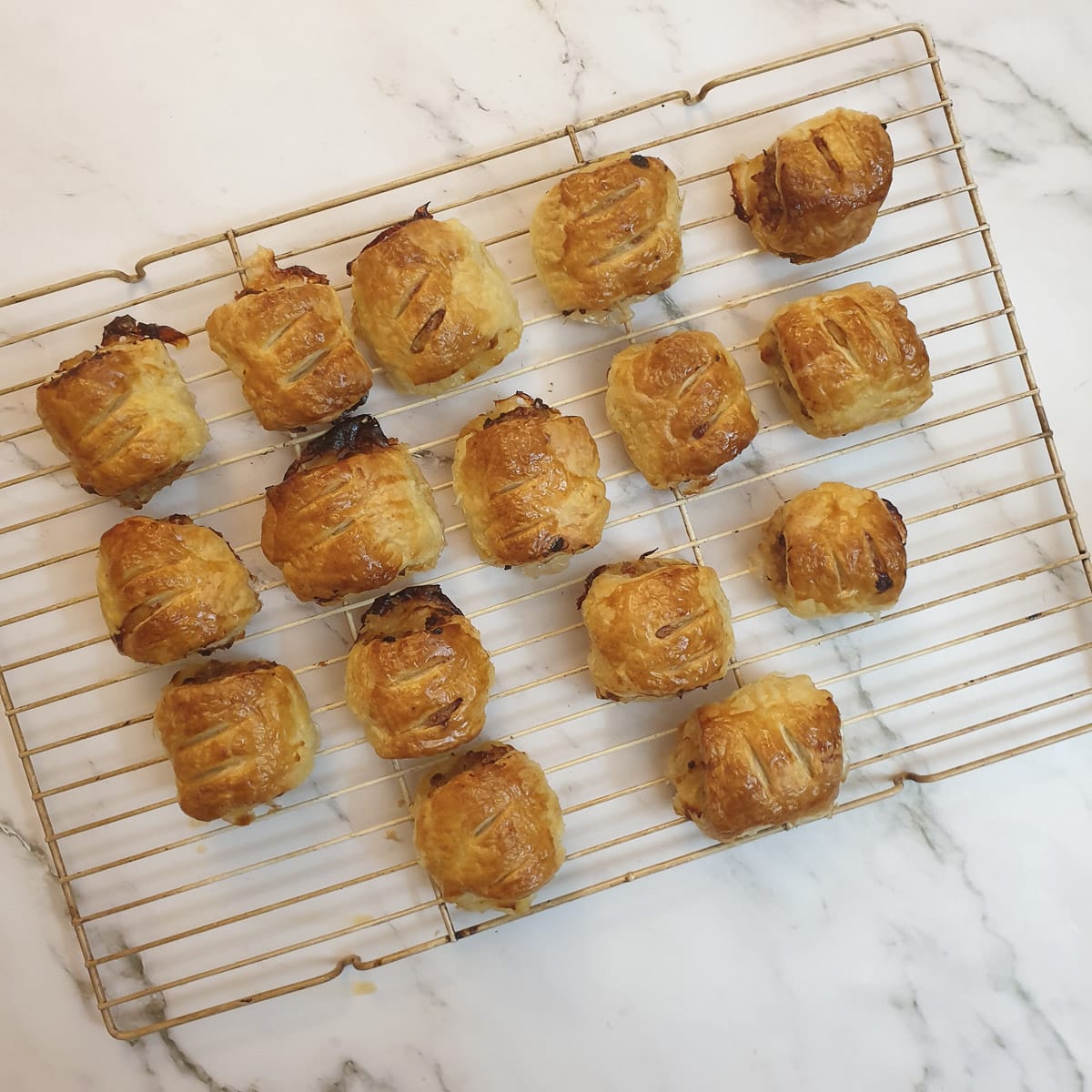 Baked sausage rolls on a cooling rack.