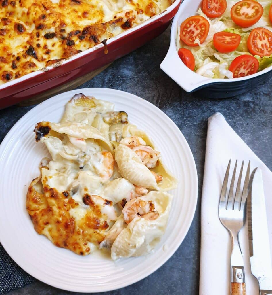 A plate of seafood stuffed pasta shells covered in cheese sauce.